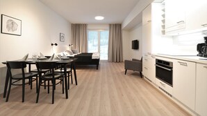 Une cuisine moderne avec des meubles blancs, un four encastré et un coin repas comprenant une table et des chaises.