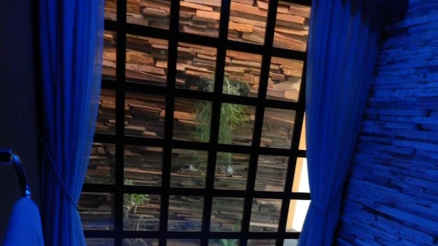 A modern bathroom with a blue-lit bathtub, wooden paneling, and a view of greenery outside. - Pousada e Motel Blue Inn (Cascavel)