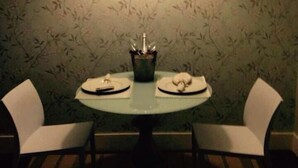 A dining area with two white chairs, a round table, and a small table lamp. - Pousada e Motel Blue Inn (Cascavel)