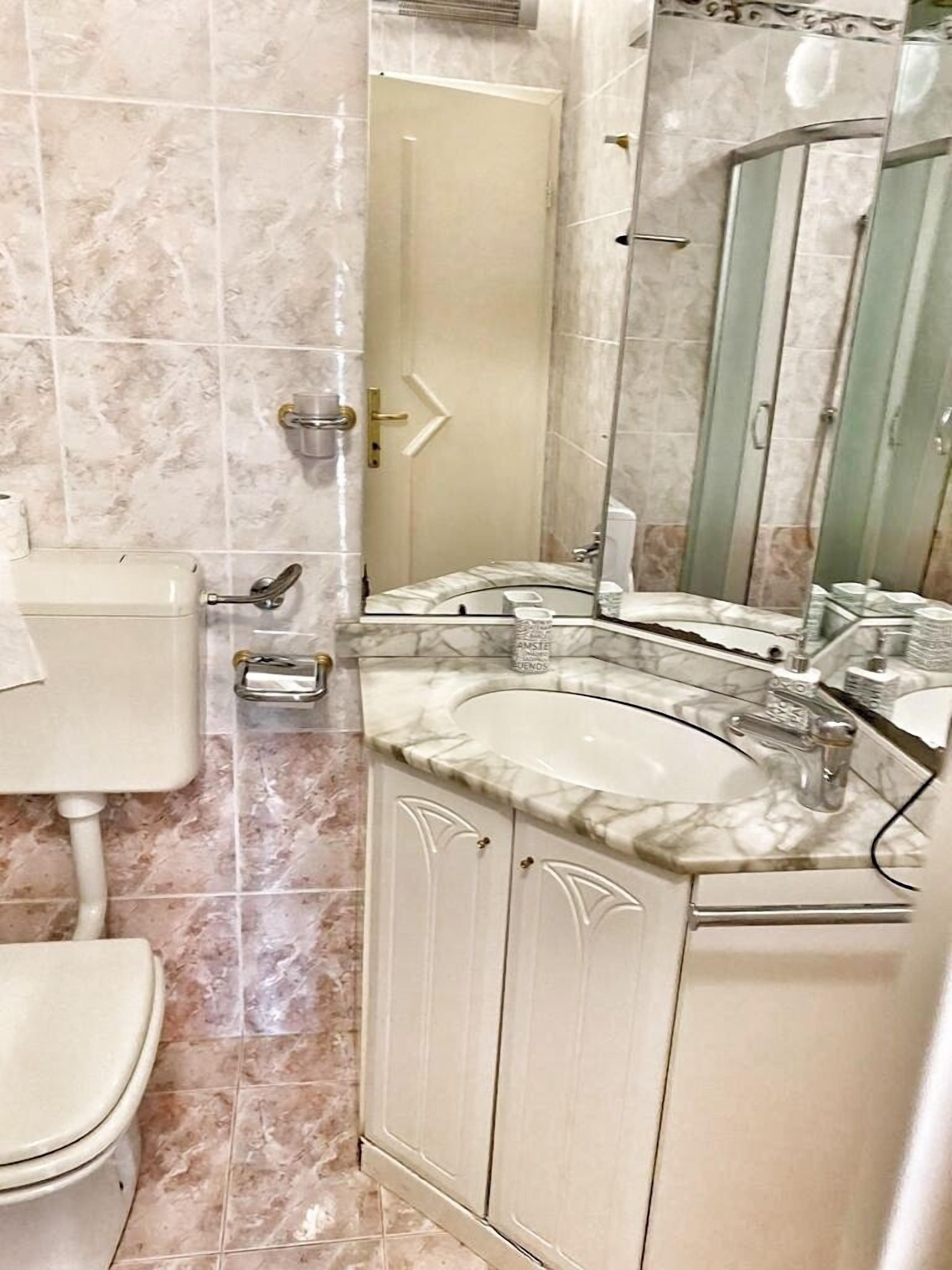 Un baño con inodoro, lavamanos y espejo.