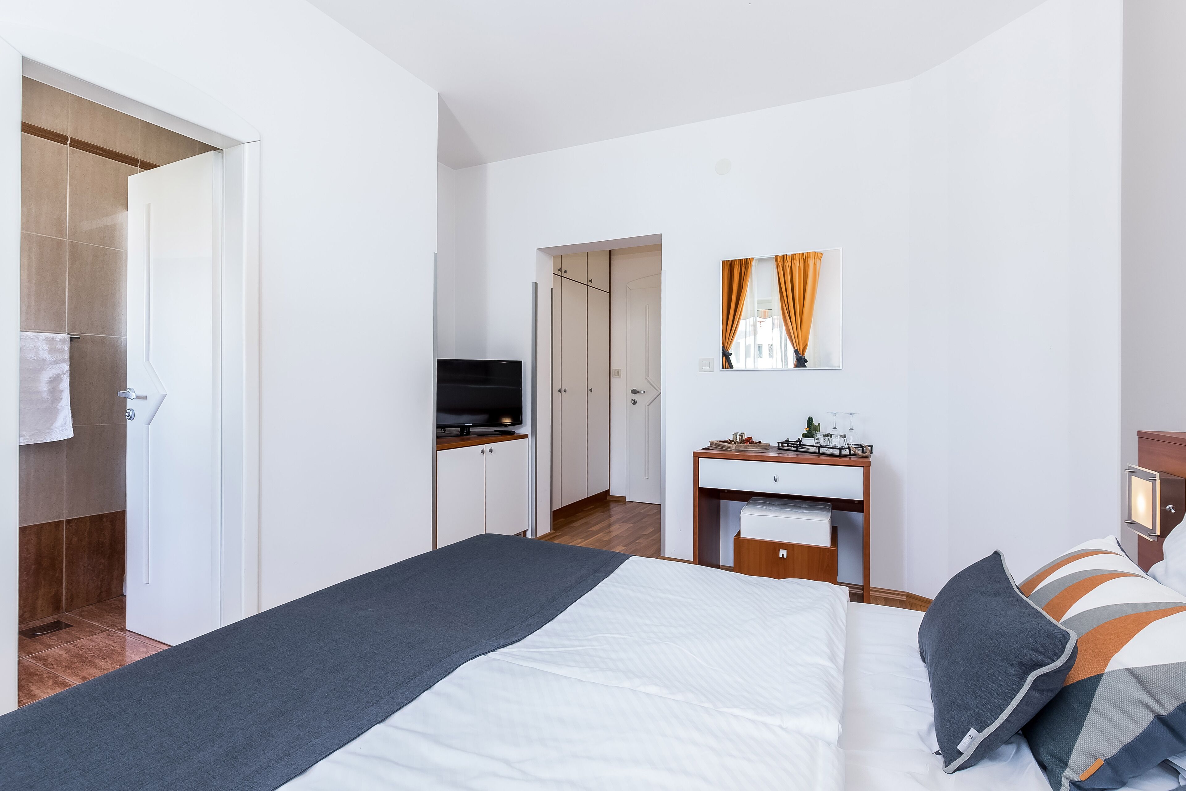 Een moderne hotelkamer met een bed, een bureau, een televisie en een badkamer die door een open deur zichtbaar is.