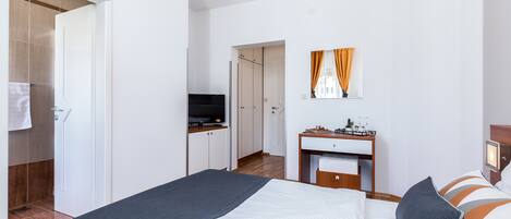 Ein modernes Hotelzimmer mit Bett, Schreibtisch, Fernseher und einem durchgegangenen Tür sichtbaren Badezimmer.