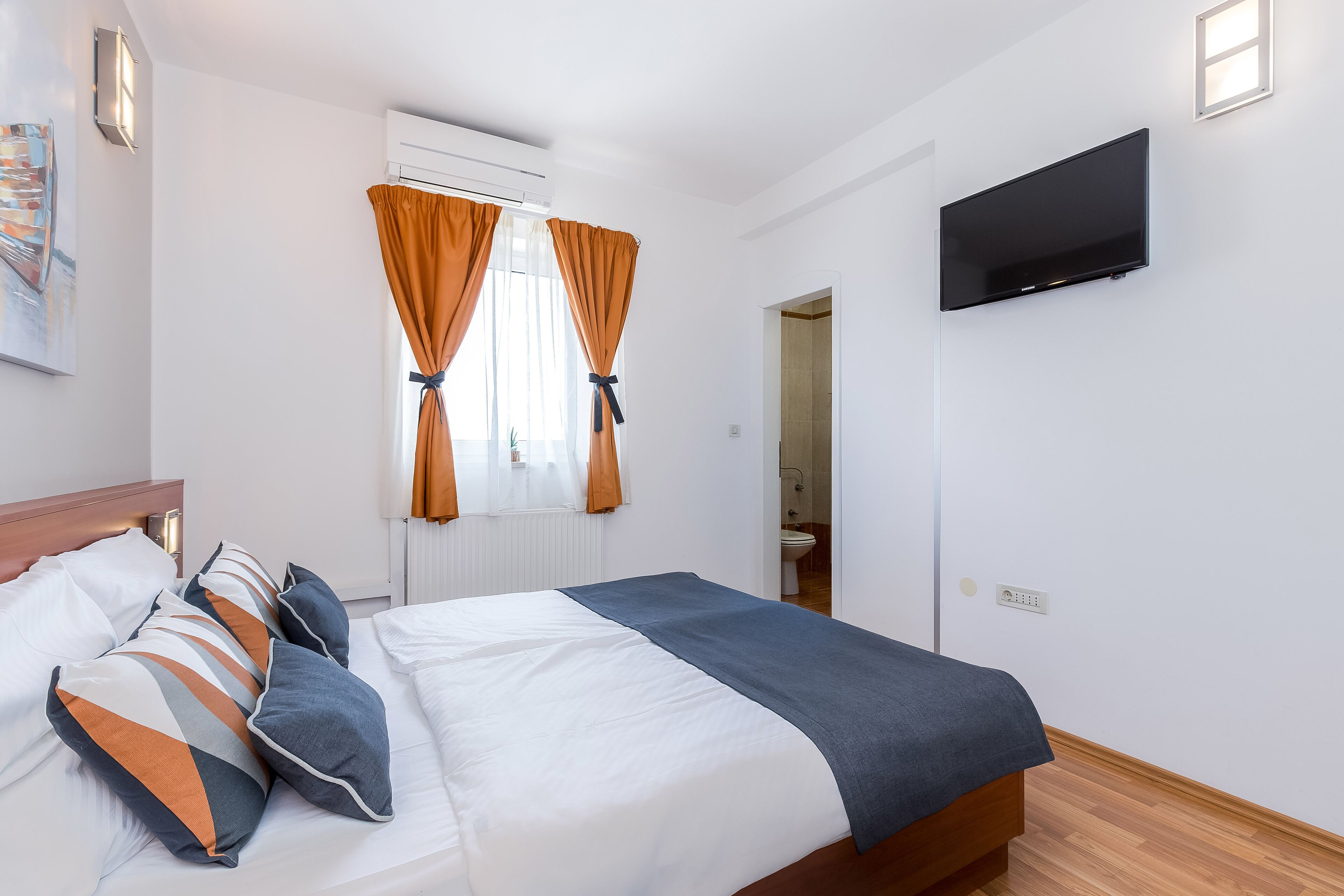 Habitación de hotel con cama, cortinas, televisor de pantalla plana y ventana.