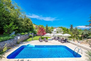 Una piscina al aire libre de temporada, sombrillas, tumbonas