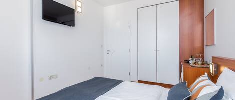 Egy szállodai szoba, amelyben található egy ágy, a falra szerelt televízió, egy fa szekrény és egy kis asztal, melyen egy tálca van, tele különböző tárgyakkal.