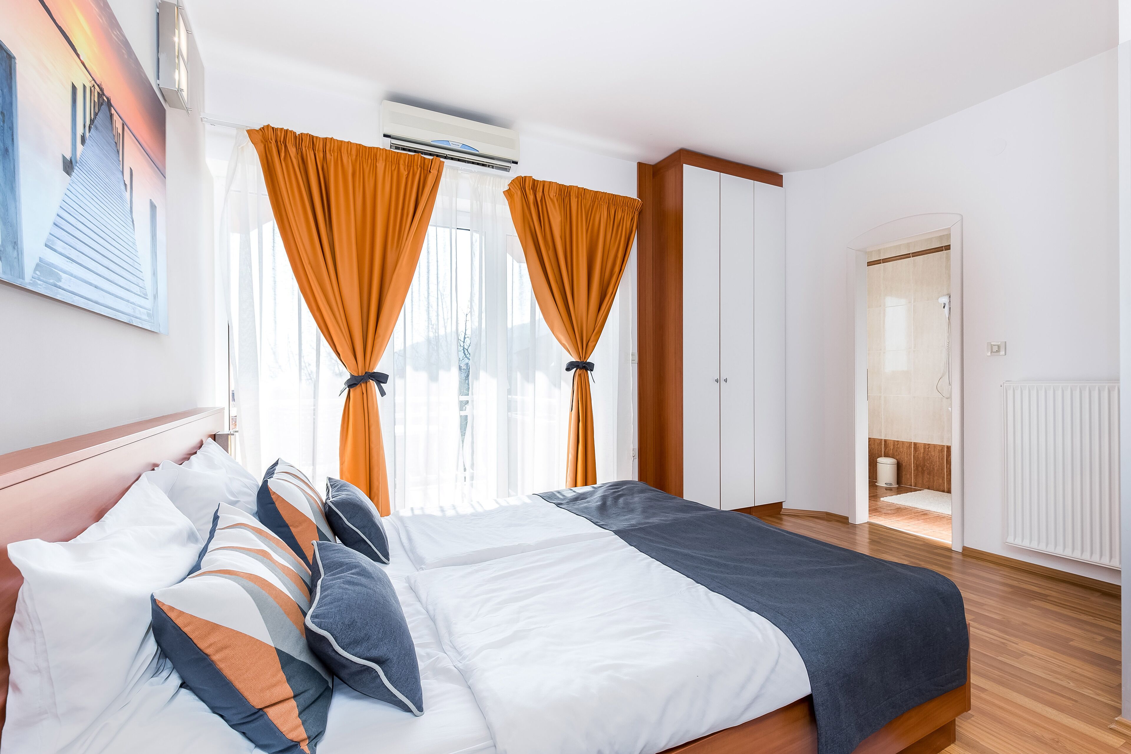 A hotel room with a bed, a wardrobe, and a bathroom visible through an open door.