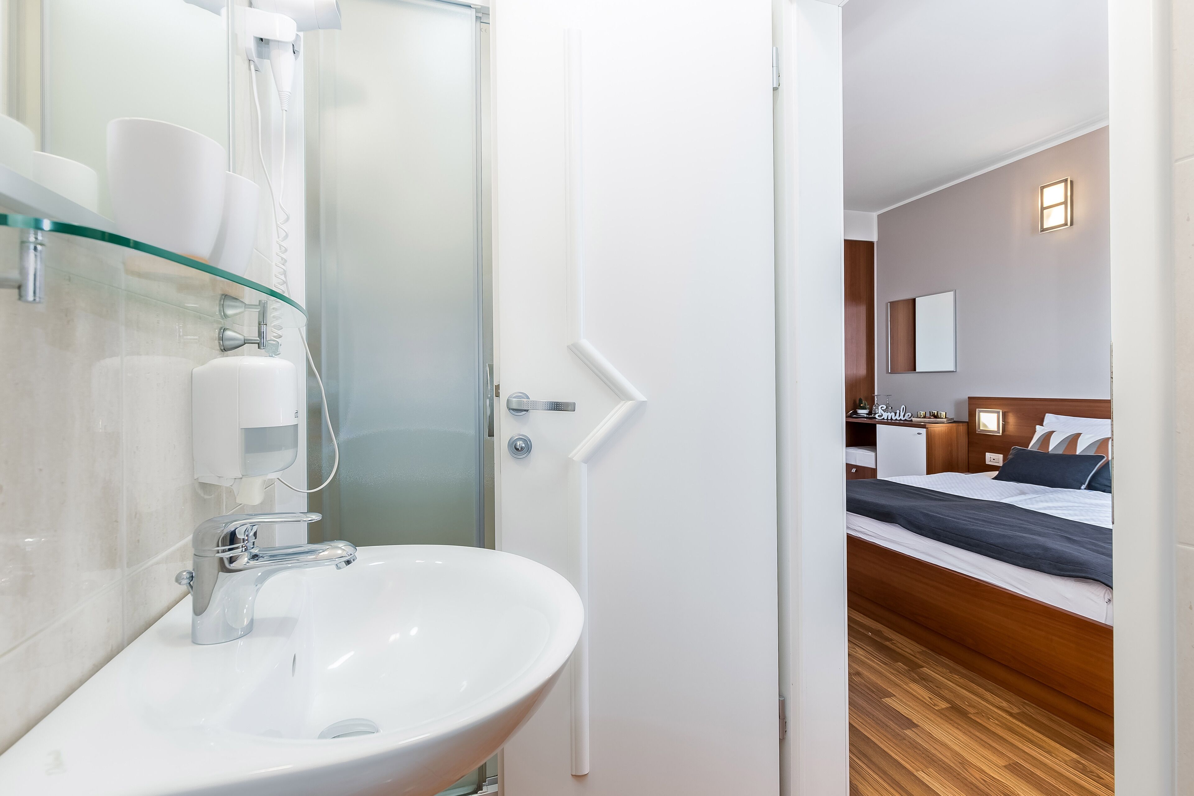 A modern bathroom with a glass shower enclosure, a white sink, and a white toilet.