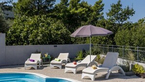 Et poolområde med hvide liggestole og en lilla parasol.