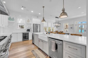 Una cocina moderna con armarios blancos, electrodomésticos de acero inoxidable e iluminación colgante.