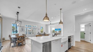 A spacious kitchen with a large island, white cabinetry, and pendant lighting.