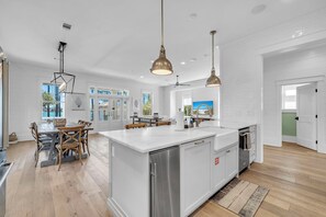 A spacious kitchen with a large island, white cabinetry, and pendant lighting.