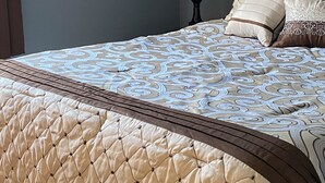 A neatly made bed with a patterned bedspread and a quilted duvet. - At home feeling with amenities. (Branson)