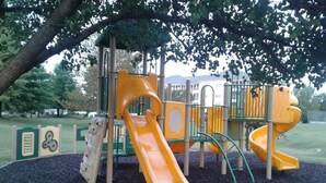 A playground with two yellow slides and a climbing structure. - At home feeling with amenities. (Branson)