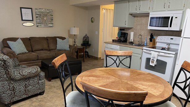 A compact living space with a sofa, a dining table with chairs, a coffee machine, and a microwave. - At home feeling with amenities. (Branson)