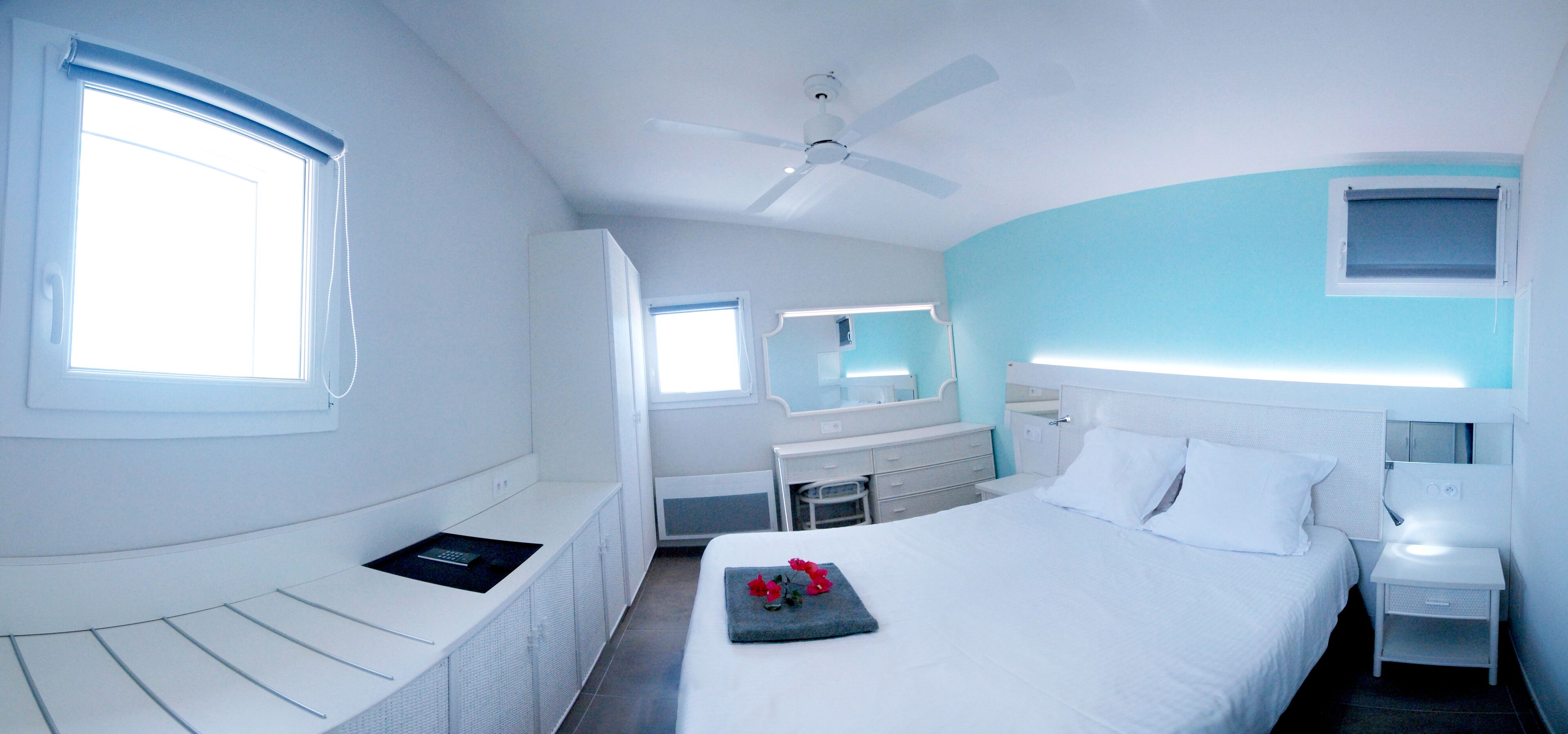 A modern hotel room with a bed, bedside table, and a desk with a chair.