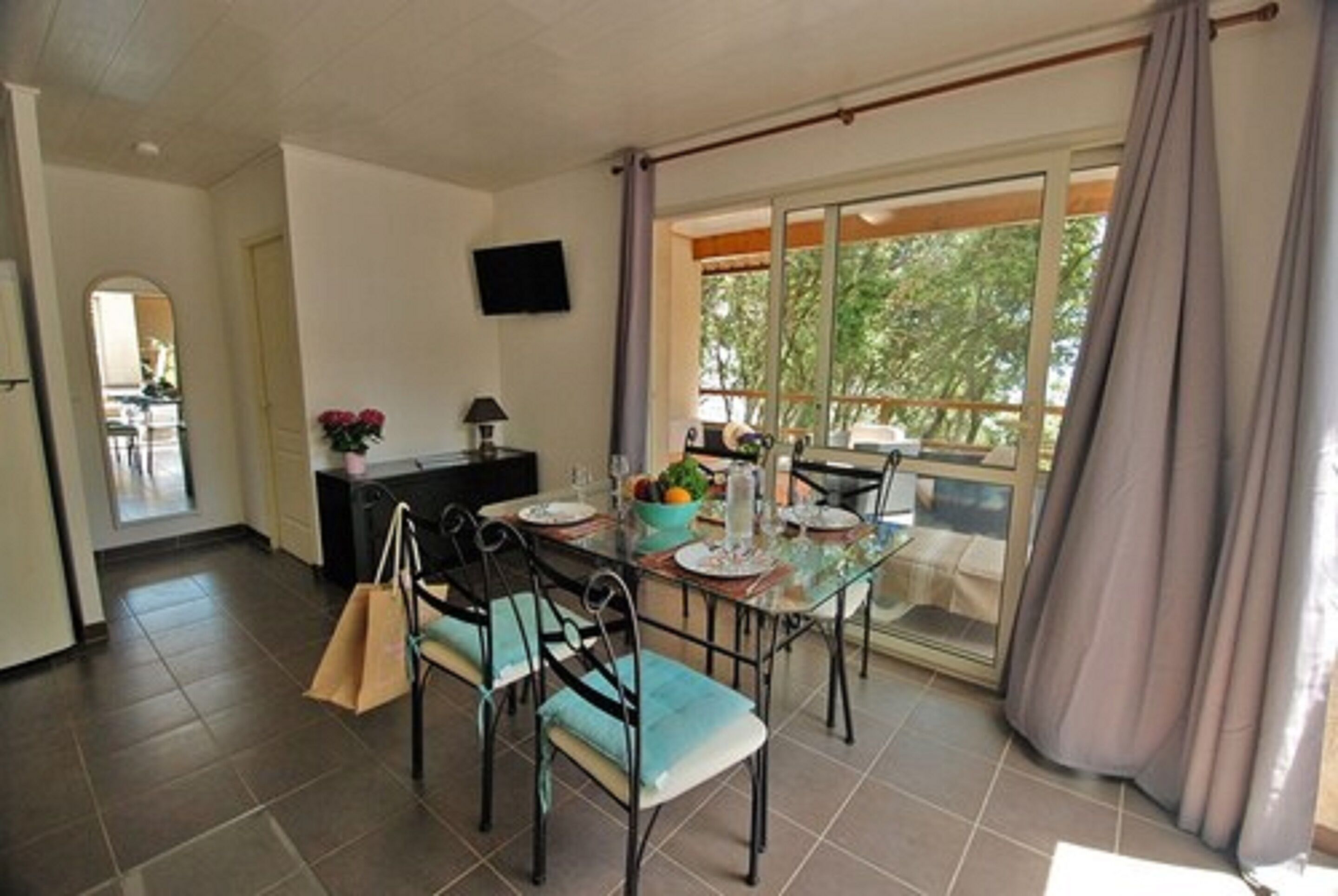 A dining area with a glass table, chairs, and a view of the outdoors.