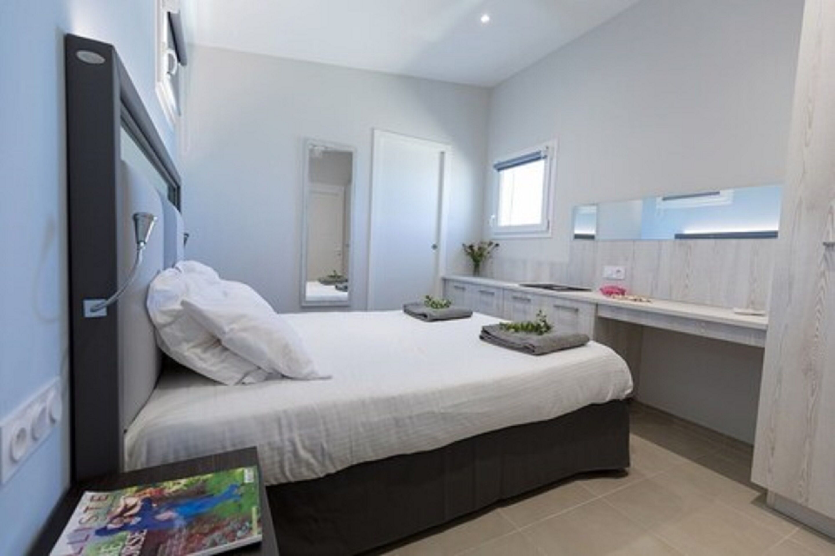A modern bedroom with a bed, bedside table, and a window.