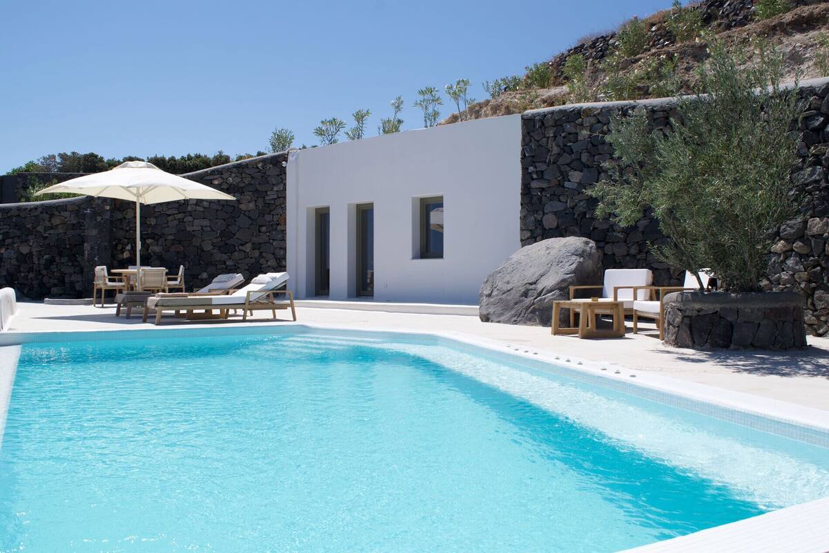 A swimming pool with lounge chairs and a stone wall.