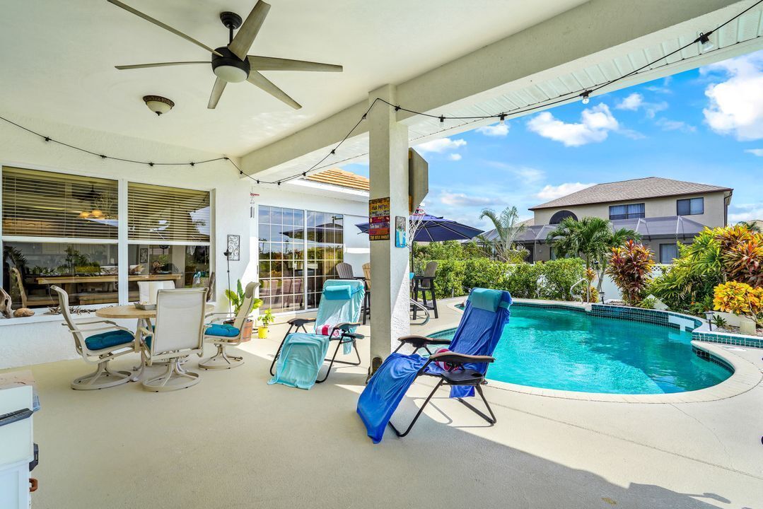 An indoor pool area with lounge chairs and a ceiling fan.
