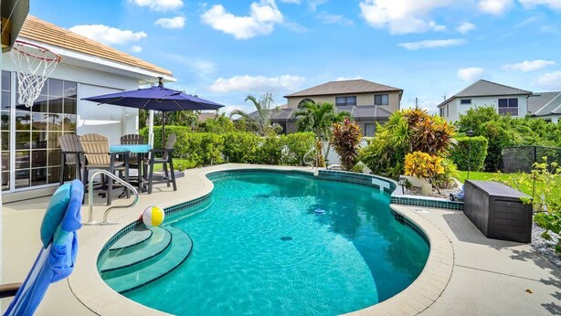 Un jardin avec une piscine, un panier de basketball et du mobilier d’extérieur.