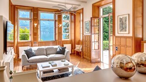 Un salon spacieux avec une grande fenêtre, un canapé, une table basse et un miroir décoratif.