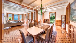 Un vaste espace dédié à la salle à manger, comprenant une grande table, des chaises et un lustre.