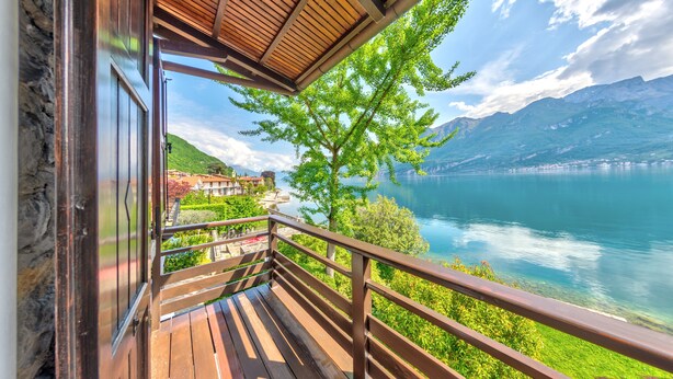 Un balcon en bois offrant une vue sur un lac et des montagnes.