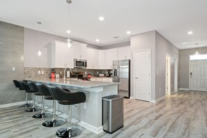 A modern kitchen with a central island, stainless steel appliances, and bar stools.