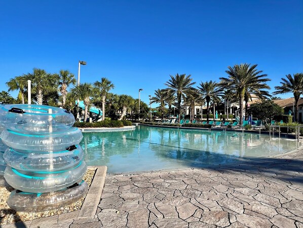A pool area with clear blue water, surrounded by palm trees and lounge chairs.