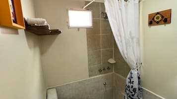 A small bathroom with a wooden ceiling, a shower, a toilet, a bidet, and a sink.