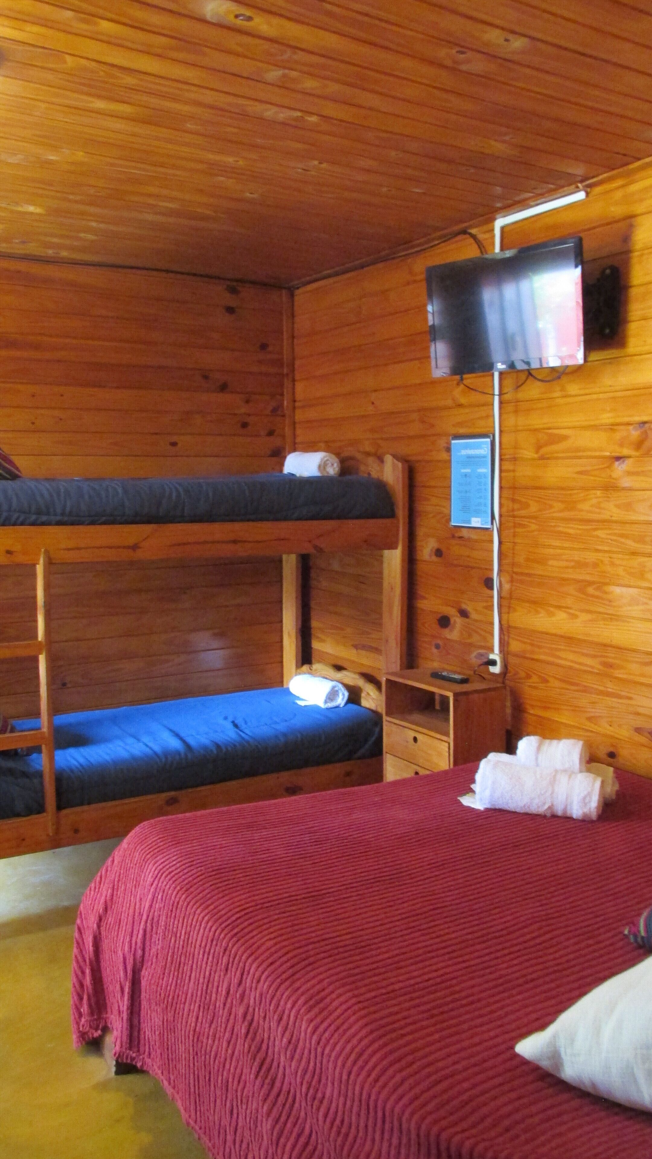 A wooden cabin room with bunk beds, a television, and a small table.