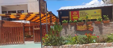 Une auberge de jeunesse avec une enseigne indiquant la présence de chambres privées, un mur en pierre et des plantes en pot.
