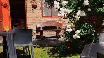 Un área de recepción con un edificio de ladrillo, un banco de madera y una mesa con sillas.