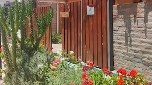 Señal de un hostal llamado "Hostal Cabanitas del Sur", con una cerca de madera y macetas con plantas en primer plano.