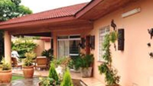 A building with a red roof, potted plants, and a paved area.