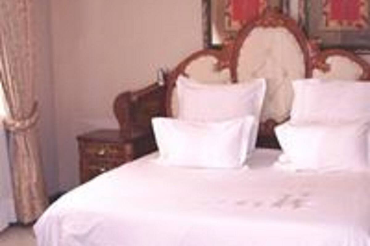 Un lit bien fait, avec du linge de lit blanc, dans une chambre dotée d’une tête de lit en bois et d’une table de chevet.
