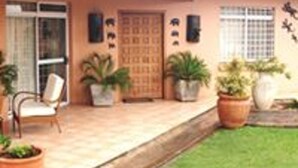 A house with a tiled porch, a wooden door, and several potted plants.