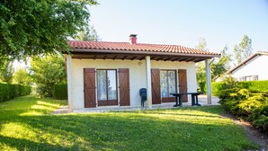 A small, single-story building with a tiled roof, a bench, and a door with shutters. - Paradise Chalets and Camping (Sarrecave)