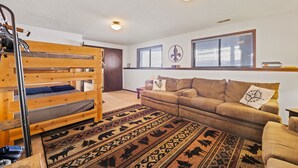 A room with a bunk bed, a sofa, a patterned rug, and a window with blinds. - Family space+ central +Private entry 2 Bedroom 1 Bath + Bunk Beds + Kitchen  (Colorado Springs)