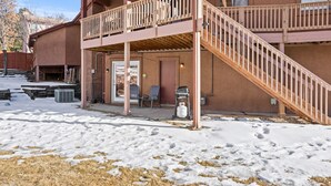 A two-story building with a covered outdoor area, wooden stairs, and a snow-covered ground. - Family space+ central +Private entry 2 Bedroom 1 Bath + Bunk Beds + Kitchen  (Colorado Springs)