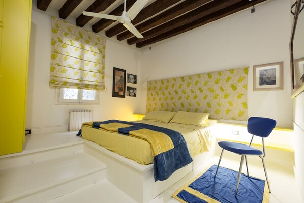 Une chambre à coucher avec un lit, une chaise et une fenêtre avec des stores.