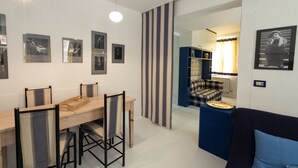 Un soggiorno moderno con zona pranzo, caratterizzato da un pannello a righe, un divano blu e un tavolo da pranzo in legno con sedie.