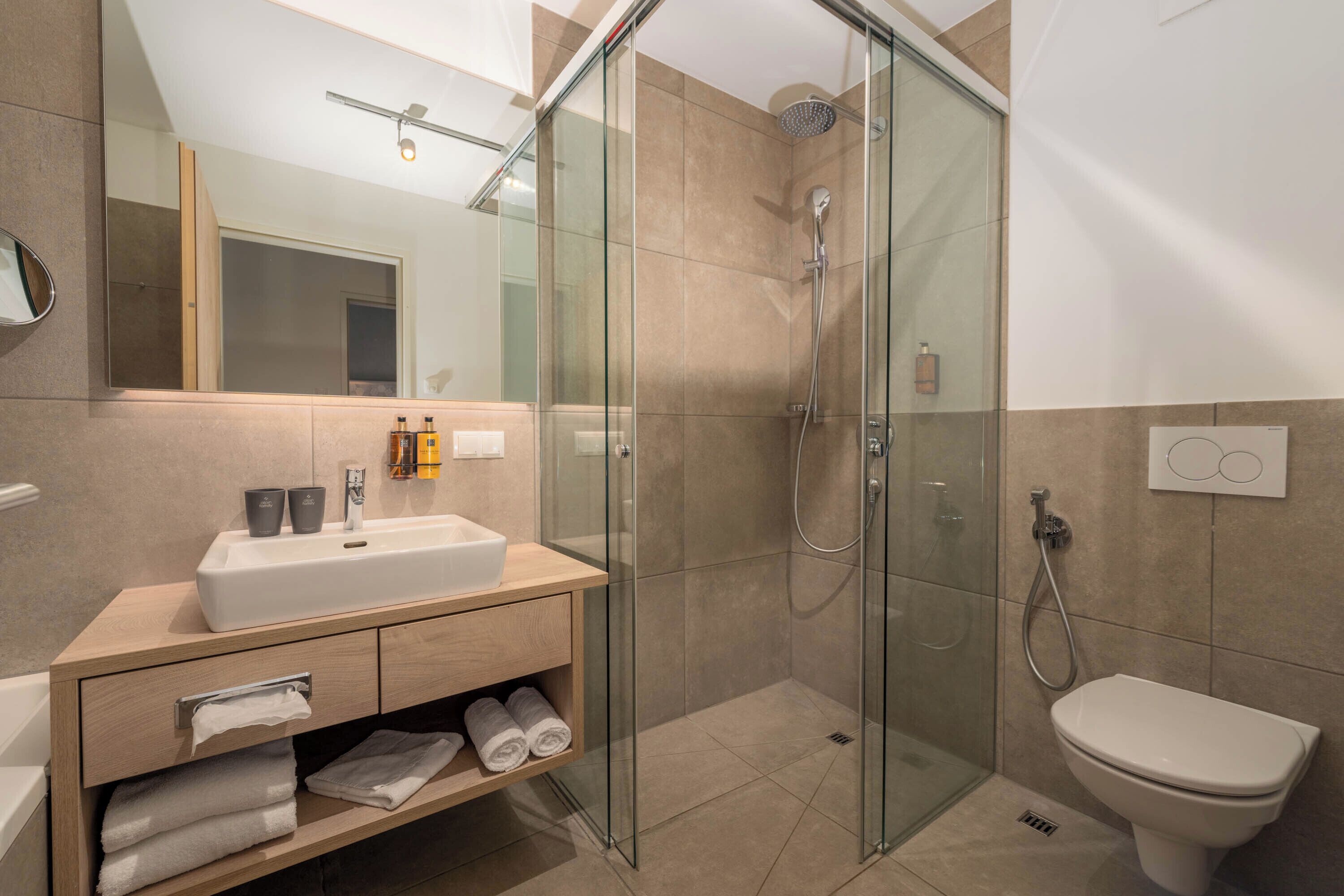 A modern bathroom with a glass-enclosed shower, a white sink, and a toilet.