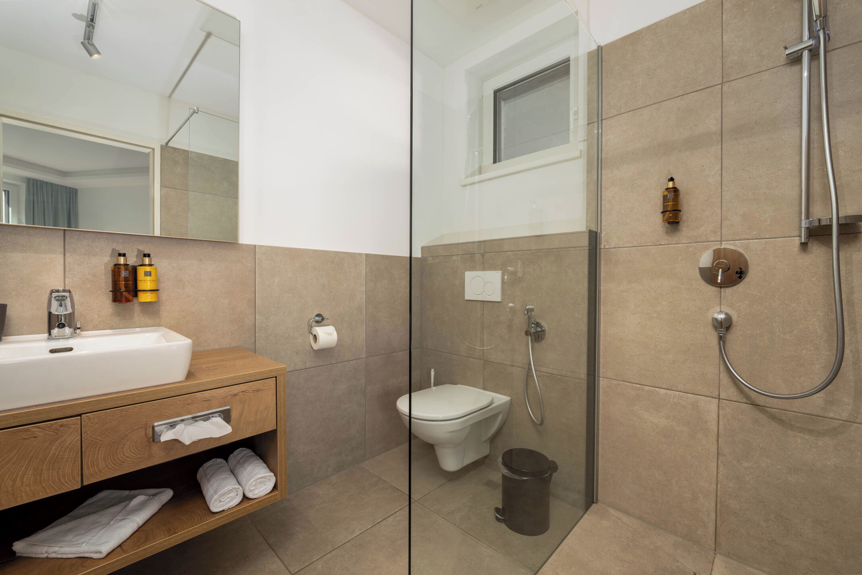Een moderne badkamer met een wastafel, toilet en douche.