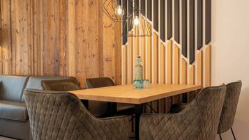 Un comedor con una mesa de madera, sillas acolchadas, una botella y una lámpara colgante moderna.