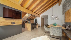 Una cocina moderna con techo de madera, una isla central con taburetes de bar y un comedor con mesa y sillas.