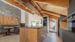 Una cocina moderna con isla de madera, electrodomésticos integrados y una zona de comedor con mesa y sillas.