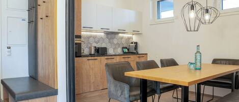 A modern kitchen with wooden cabinets, a built-in bench, and a dining area with a wooden table and chairs.