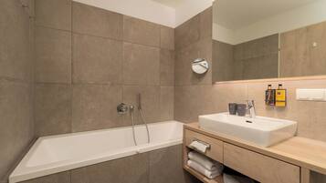 A modern bathroom with a large bathtub, a sink, and a mirror.