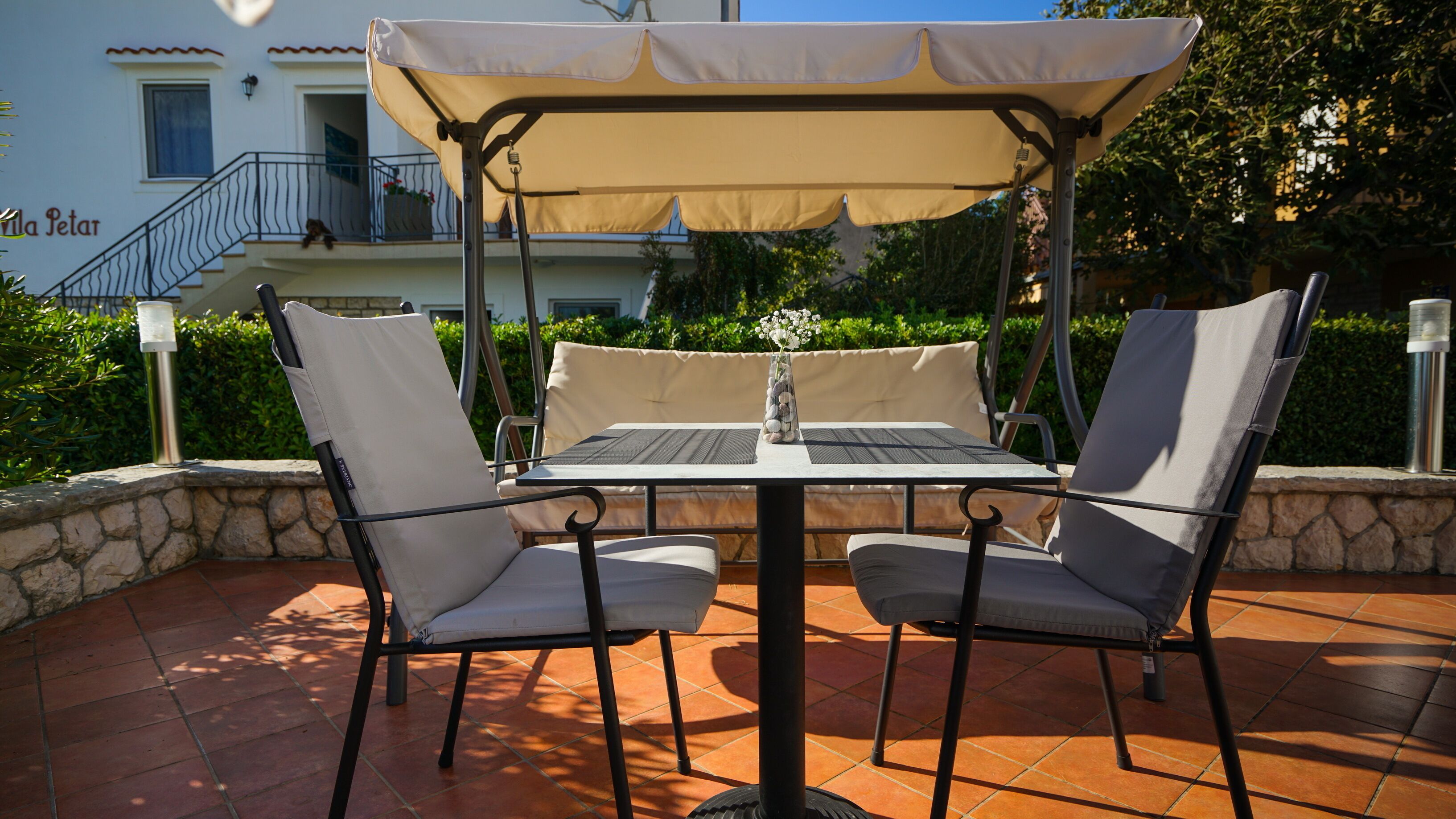 An outdoor patio with a table and chairs, a canopy, and a view of a building with balconies.